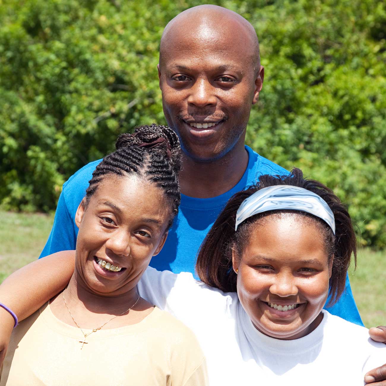 Smiling family outdoors with two adults with developmental disabilities and their caregiver